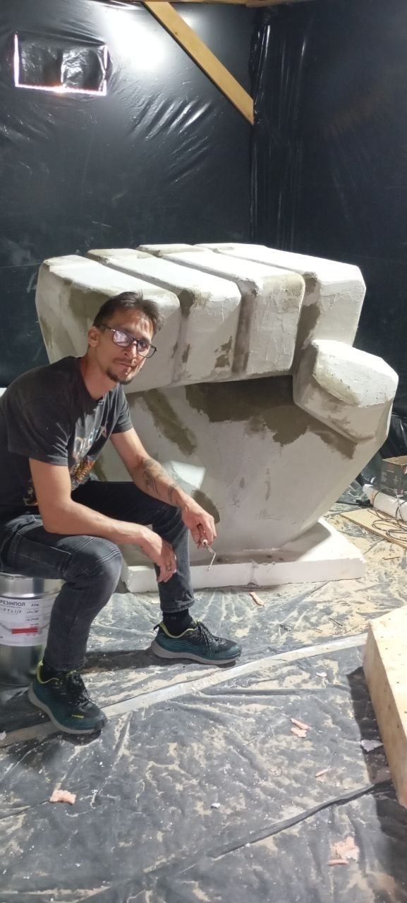 Майстер Андрій Губійчук поруч зі скульптурою кулака солідарності